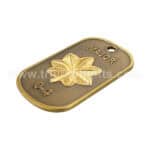 Golden military badge with leaf emblem and engraved rank and unit details.