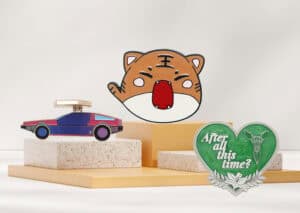 Colorful custom promotional items including a car-shaped accessory, a playful cartoon tiger face, and a green heart-shaped badge with "After all this time?" message, perfect for branding and awards.