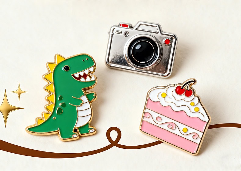 Bright enamel pins featuring a cute green dinosaur, a camera, and a slice of pink cake with cherries, perfect for customization and promotional giveaways.