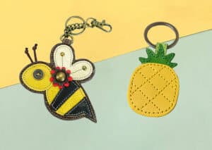 Colorful handcrafted bee and pineapple-themed keychains made from synthetic leather, ideal for promotional gifts, awards, or personalized accessories, showcasing custom embroidery and vibrant design.