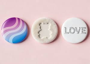 Colorful custom button badges with unique designs, including a wave pattern, a bear-shaped cutout, and the word "LOVE" embossed, perfect for promotional and branding purposes.