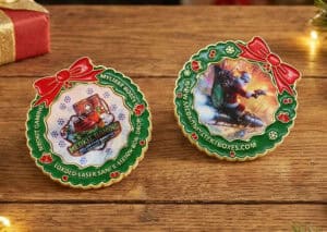 Two colorful custom lenticular coins with holiday-themed designs, featuring festive bows and detailed images, displayed on a wooden surface.